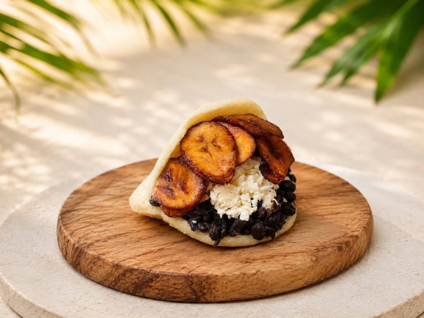 Arepa vegetariana con tajadas, caraotas negras y queso blanco.
