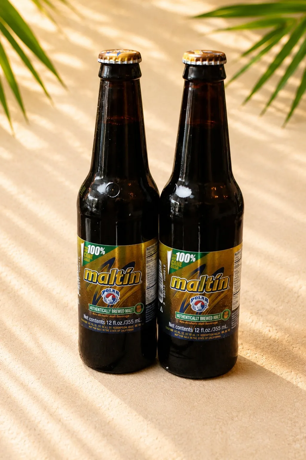 Two bottles of Maltín Polar, a Venezuelan non-alcoholic malt drink, in warm light.